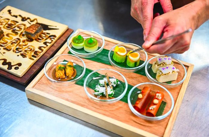 A chef arranges a large platter featuring six vibrant dishes.