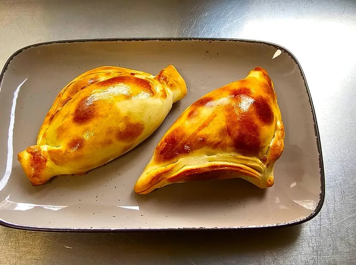 A pair of golden empanadas arranged on a tray.