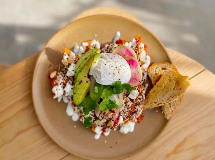 An aerial view of a dish garnished with sauce, cheese, avocado, and slices of radish.