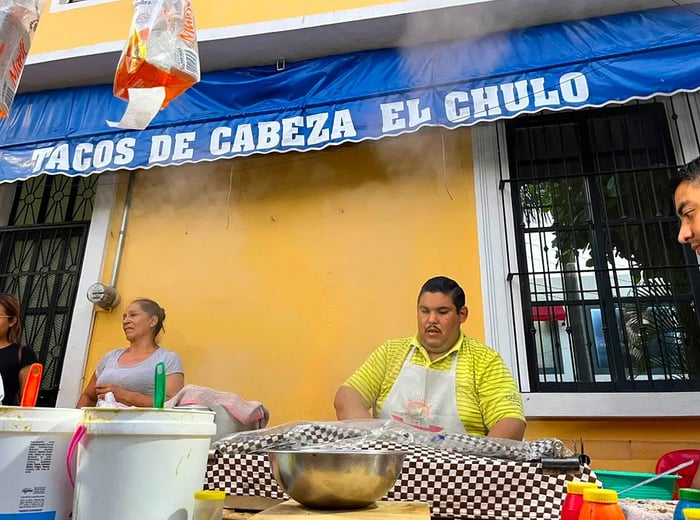 Chefs busy at work behind an outdoor preparation table.