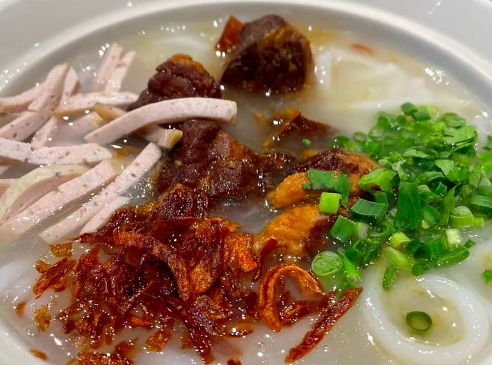 A bowl of khao piak adorned with various meats and vegetables.