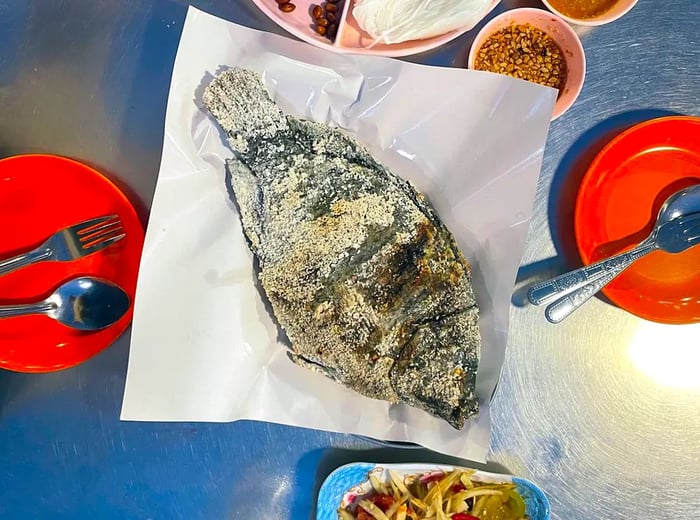 A whole, salt-encrusted fish served with a variety of sides.