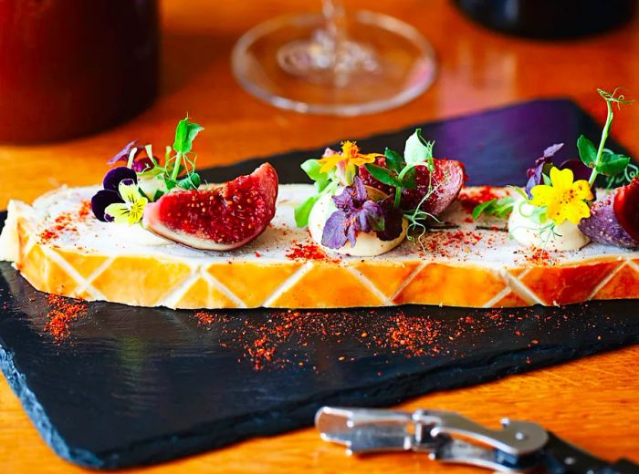 A beautifully arranged slice of pate en croute, elegantly adorned with fruits and edible flowers.