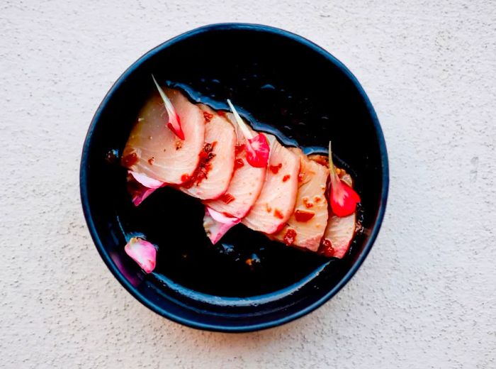 Thin slices of hamachi garnished with vegetables.