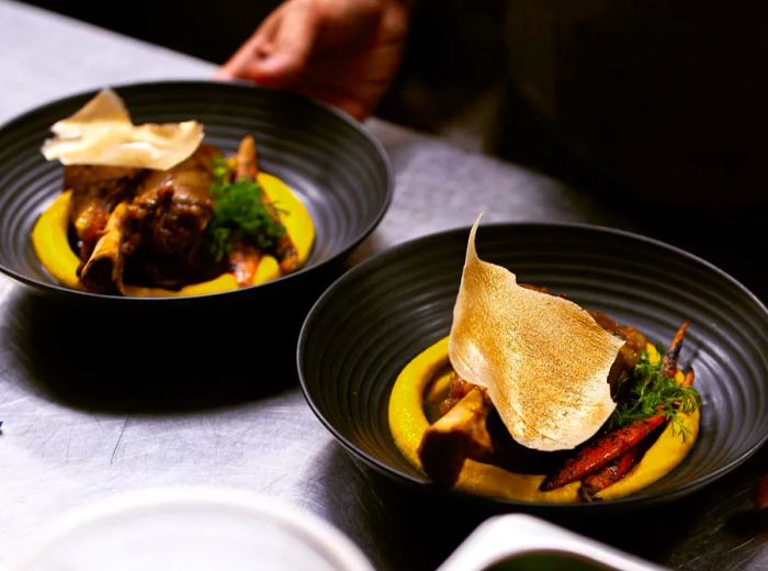 A server elegantly presents an array of intricate dishes in a dimly lit room.