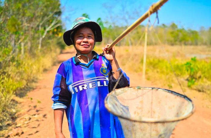 A woman holds a large net affixed to a long pole.