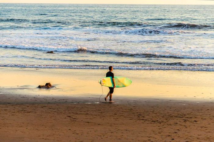 A surfer strolling along the beach with their surfboard in Central America