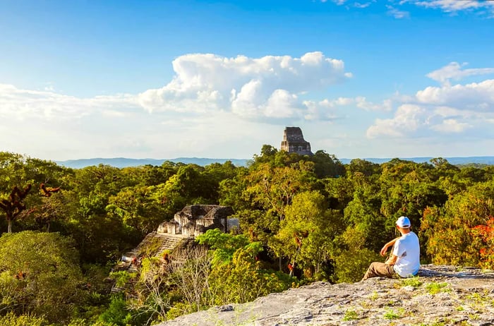 Tourist gazing at ancient Mayan ruins from a high vantage point (Temple IV and El Mundo Perdido), Tikal, Guatemala