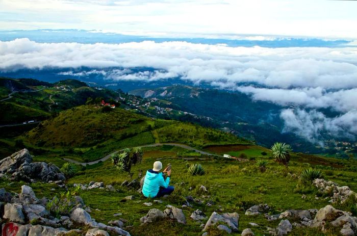 A man gazes over rolling green hills and misty clouds in the Guatemalan highlands.