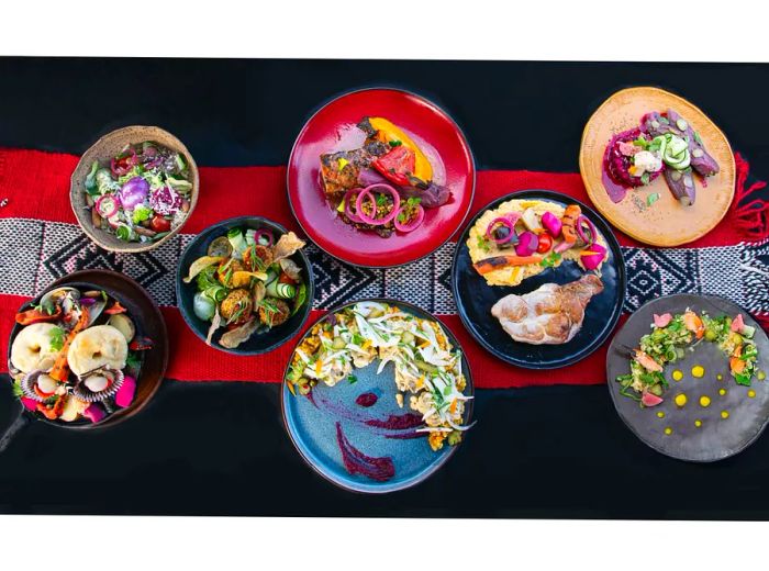 A variety of dishes beautifully arranged on a red and gray table runner.