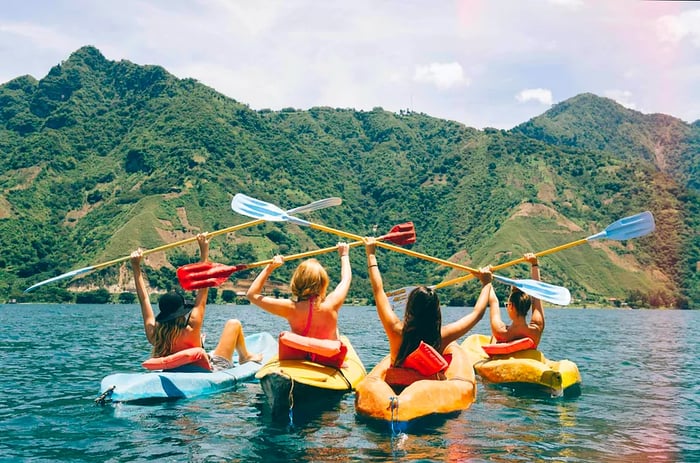 A rear view of four female friends joyfully kayaking on Lake Atitlán, Guatemala.