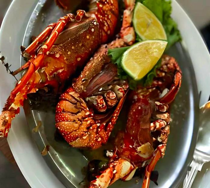 A plate featuring three large shellfish accompanied by lime wedges.