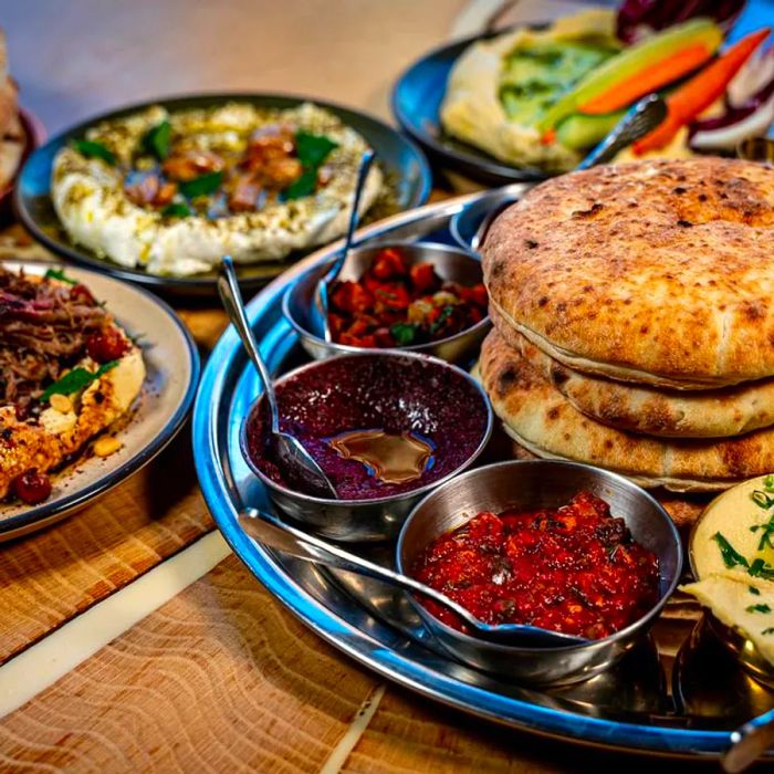 A platter of pita bread accompanied by various condiments and additional dishes.