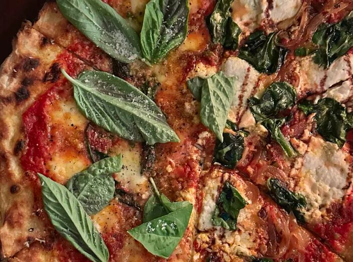 A close-up view of a pizza garnished with fresh basil leaves.