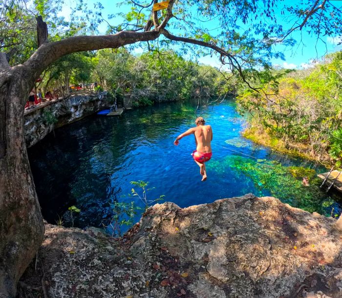 A man jumping from a cliff into the waters of Cenote Eden near Playa del Carmen;