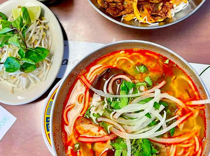 A hearty bowl of red rice noodles accompanied by various condiments and a flavorful meat rice dish.