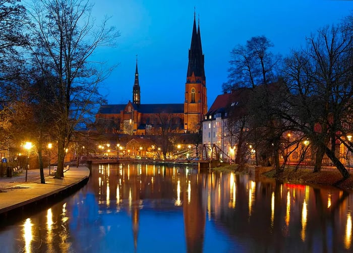 The Fyris River and cathedral shine brilliantly at night in Uppsala, Sweden.