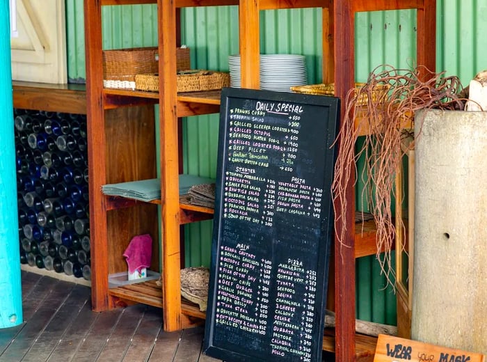 A chalkboard menu with handwritten specials, propped against some shelves.