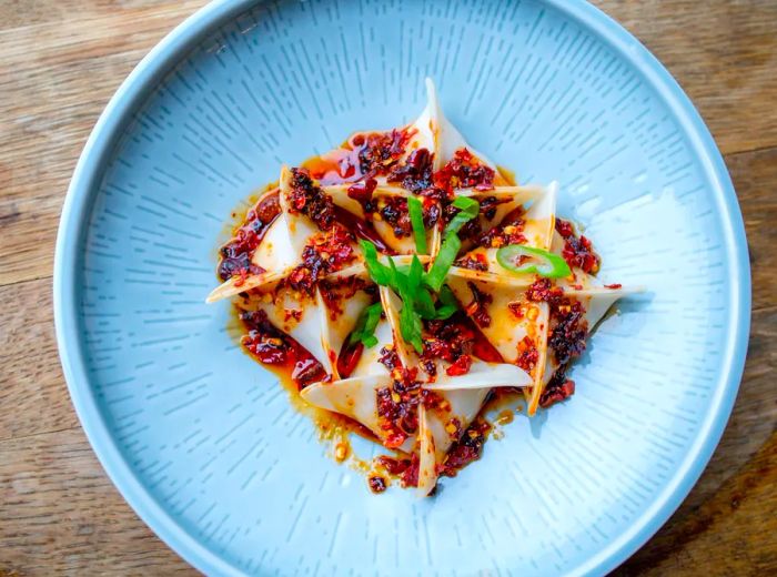 Four pleated dumplings served in a spicy chili sauce.