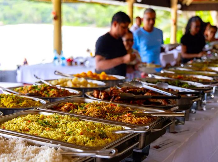 A long table filled with hot dishes of food.