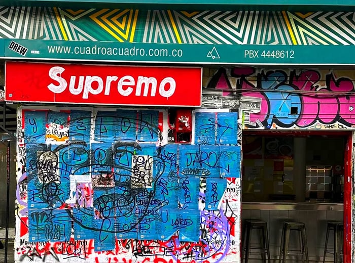 The exterior of a restaurant adorned with graffiti, featuring the name Supremo styled after the Supreme brand logo.