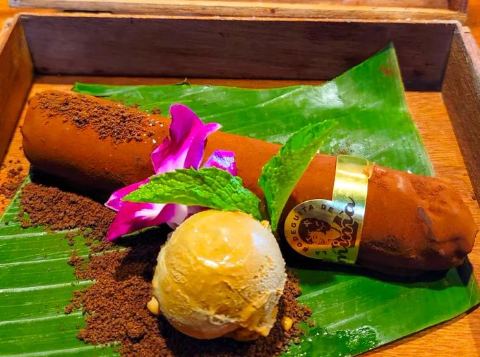 A chocolate cigar presented in a cigar box, accompanied by a generous scoop of ice cream.