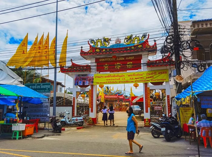 An impressive archway adorned with Thai inscriptions and a banner announcing a festival.