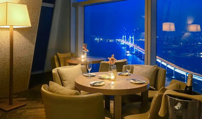 A beautifully set dining table with large windows offering a night view of the bridge.