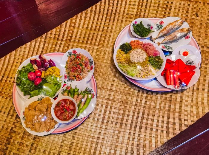 Vibrant dishes wrapped in plastic on a bamboo table.