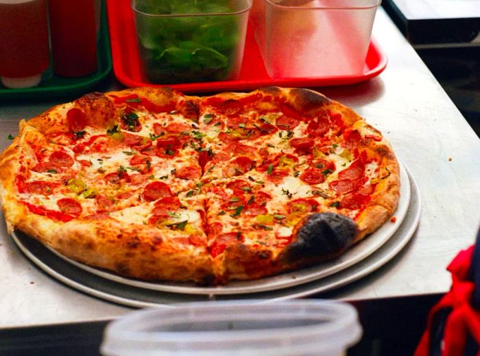 A chef carefully adds toppings to a pizza.