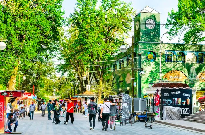 Visitors stroll along a pedestrian-friendly street adorned with trees, filled with kiosks and stalls.