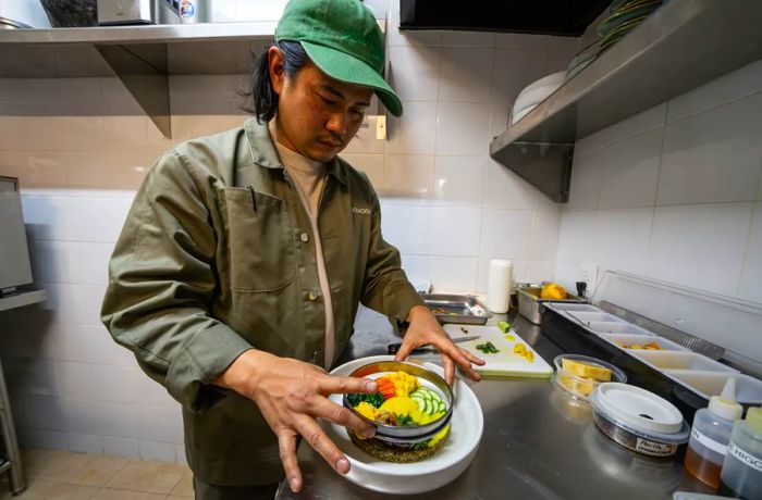 A chef carefully removes a circular mold from a vegetable dish.