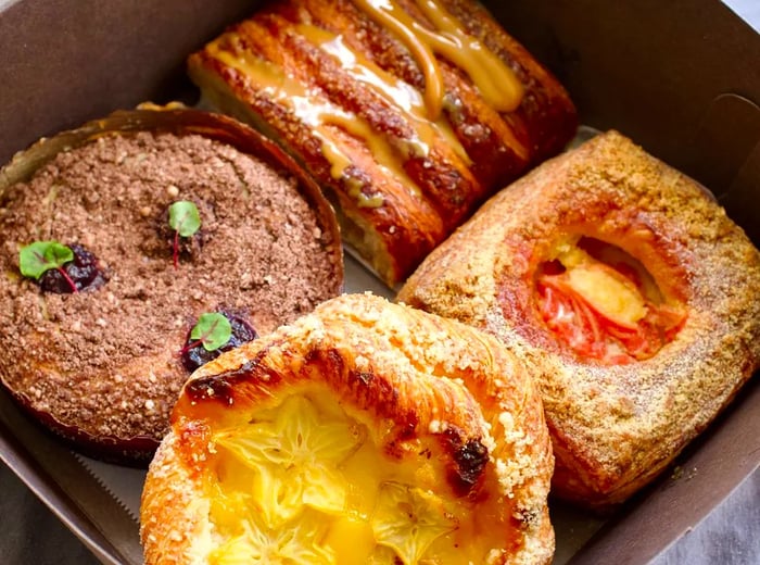 A takeout box filled with an assortment of four pastries.