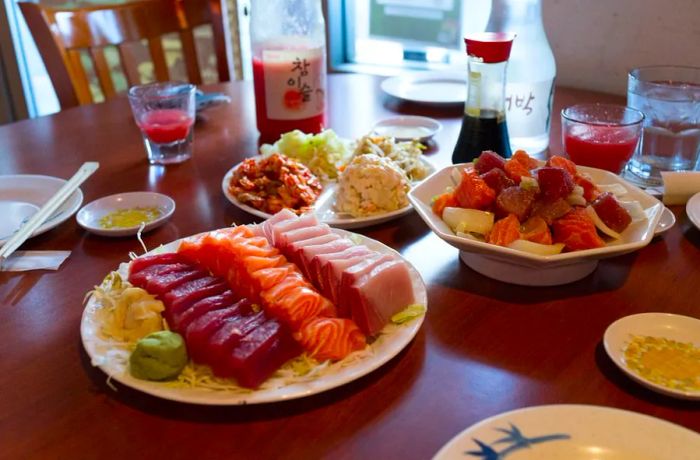 A table laden with a large sashimi platter and various other dishes.