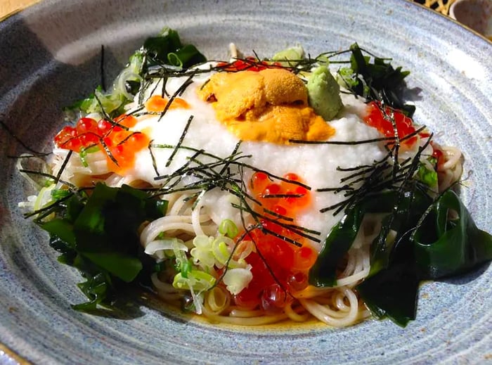 A bowl of soba adorned with uni and ikura on top.