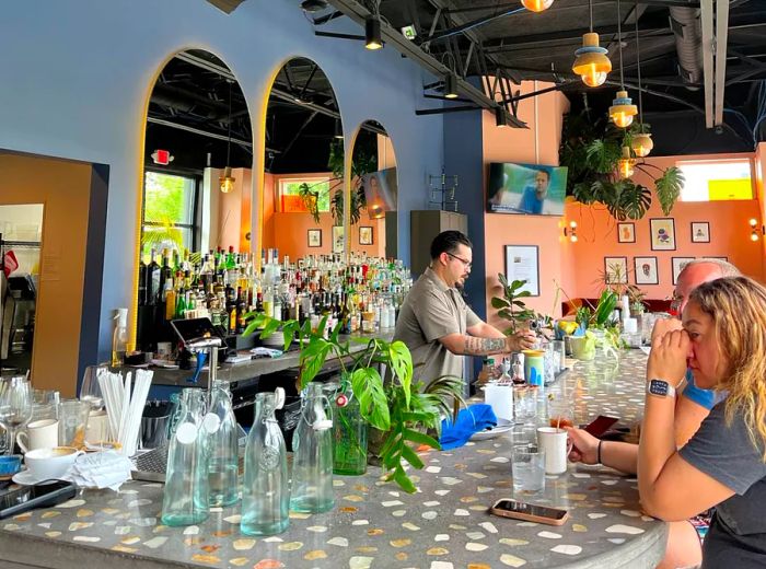 An image of a bartender serving customers at a spacious bar with high ceilings.