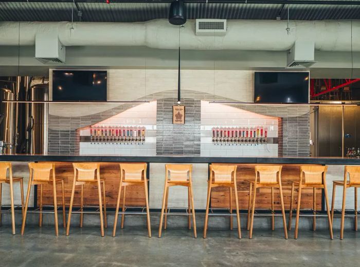 A long bar adorned with wooden stools and a gleaming row of taps behind it.