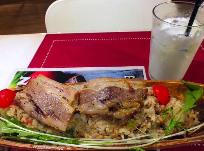 Generous pieces of meat served on a boat-shaped platter filled with rice and vegetables.