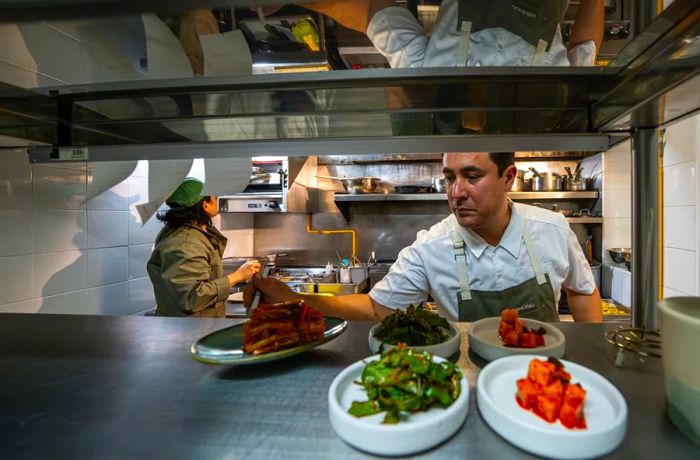 A chef arranges dishes at the pass.