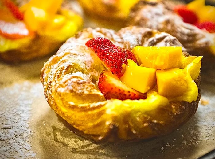 A pastry adorned with strawberries and pineapple.