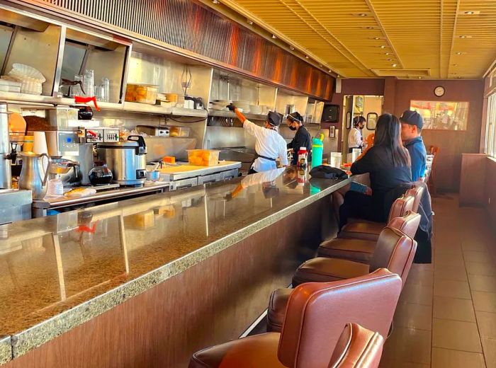 Inside the diner, patrons enjoy their meals while seated at a narrow counter.