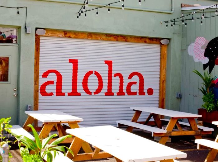 An empty patio with tables and a garage door adorned with the word aloha.