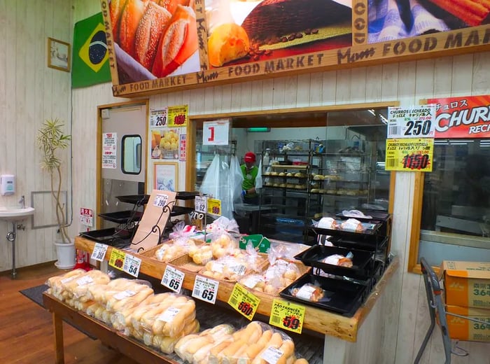 An interior view of a grocery store showcasing baked goods in front of an open kitchen.