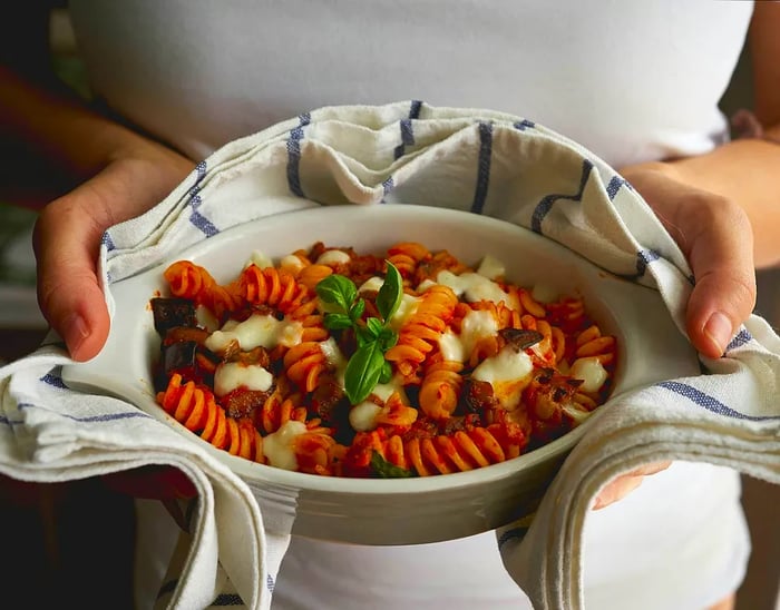 A homemade plate of fusilli 'alla Norma', a classic Sicilian dish featuring fried eggplant, mozzarella or ricotta, tomato sauce, and fresh basil. A staple of the Mediterranean diet.