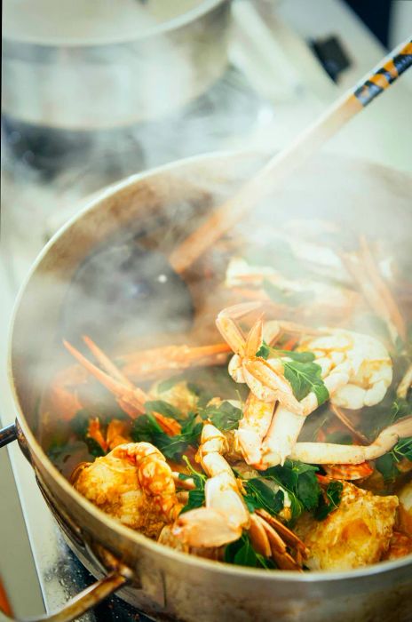 A pot of Jaffna crab curry garnished with a few murunga leaves.