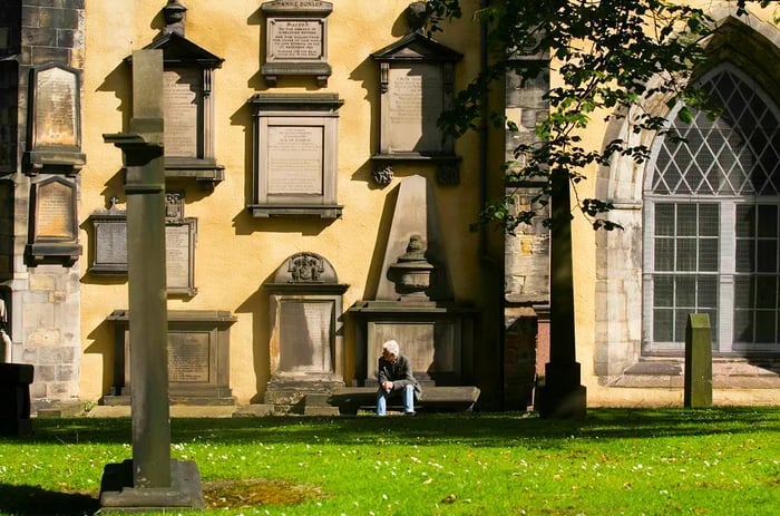 A man relaxes on a bench in Greyfriars Kirkyard.