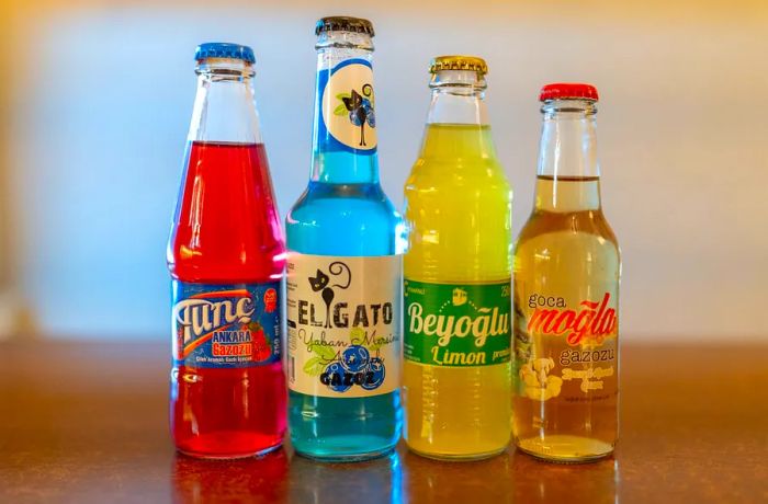 Four bottles filled with various colored sodas from four distinct gazoz brands.