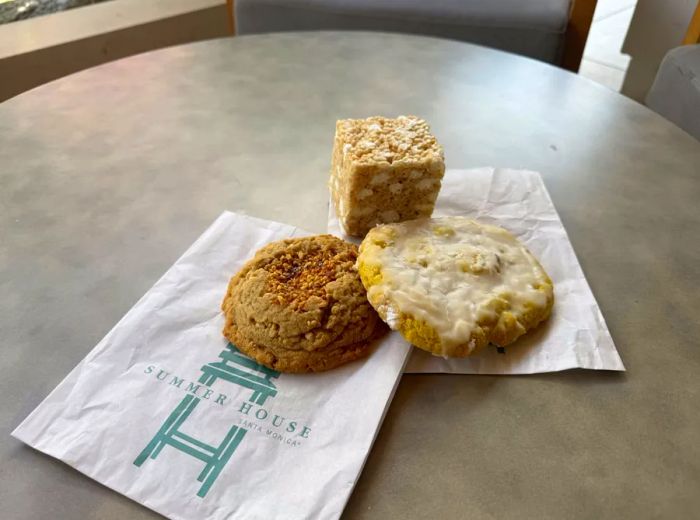 Two cookies alongside a rice krispie treat resting on branded napkins.