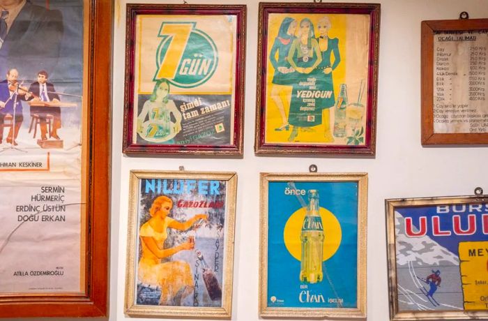 Vintage gazoz advertisements displayed in framed posters on a wall.