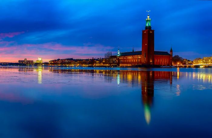 The red-brick spire of Stadshuset (City Hall) casts a reflection in the harbor at sunset, embodying the beauty of Stockholm.